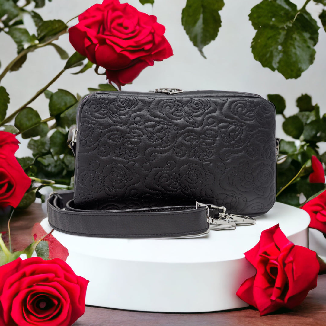 La Rosa black faux leather crossbody bag surrounded by red roses