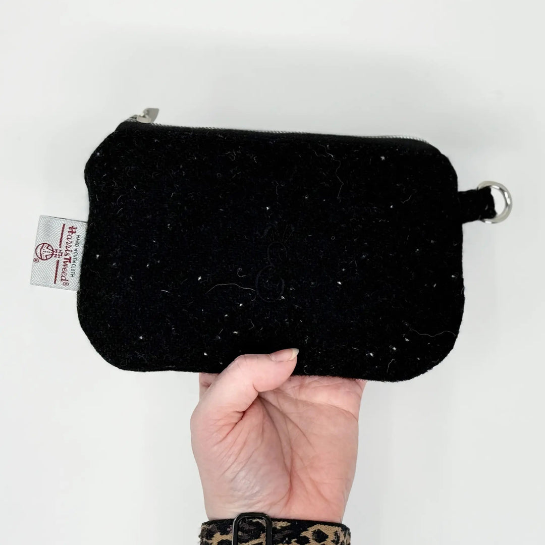 Handcrafted black Harris Tweed pouch with white nepps held in hand showing texture and 8 inch size, made in Wales