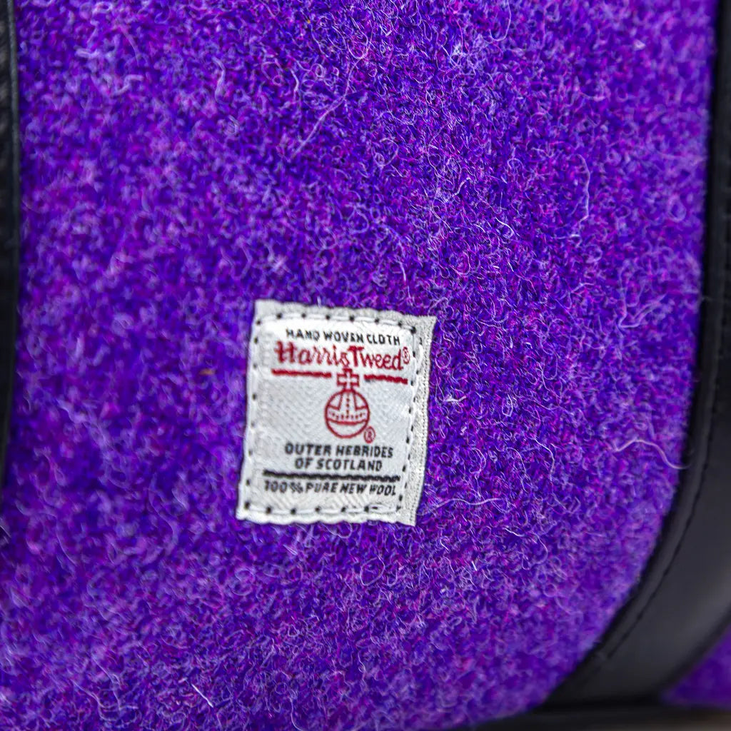 Close-up of the purple Harris Tweed® and Orb label with black leather trim on the Rowena handbag by Emma Easter Handcrafted.