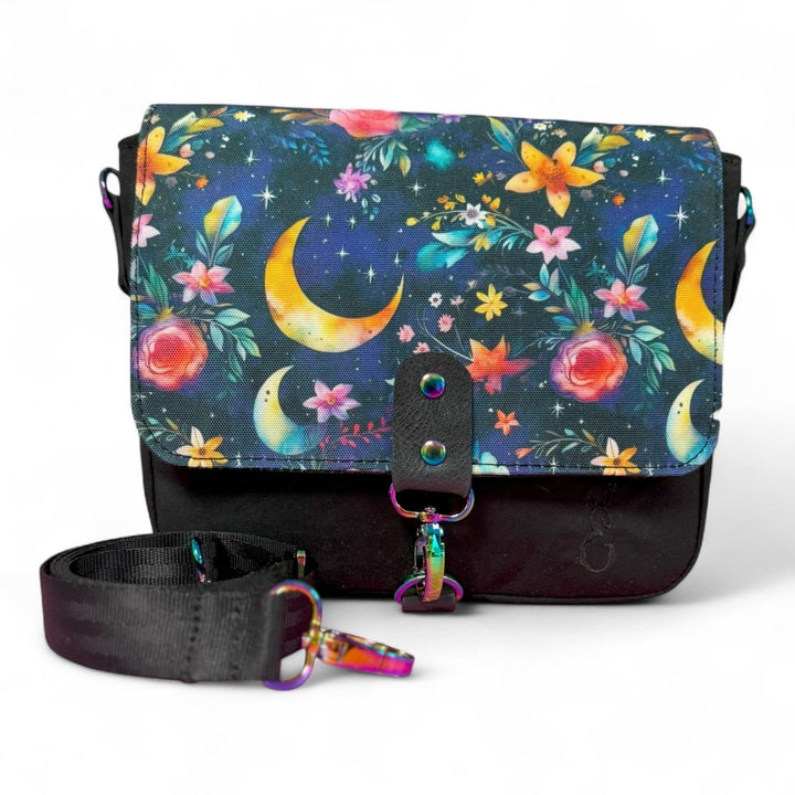Mystic Garden crossbody bag with celestial floral print flap, handcrafted with organic cotton oilskin and rainbow hardware.