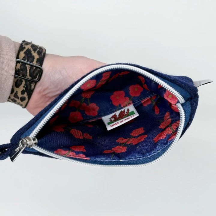 Hand holding a Navy Harris Tweed® pouch with red floral pattern lining and Made in Wales label on a white background