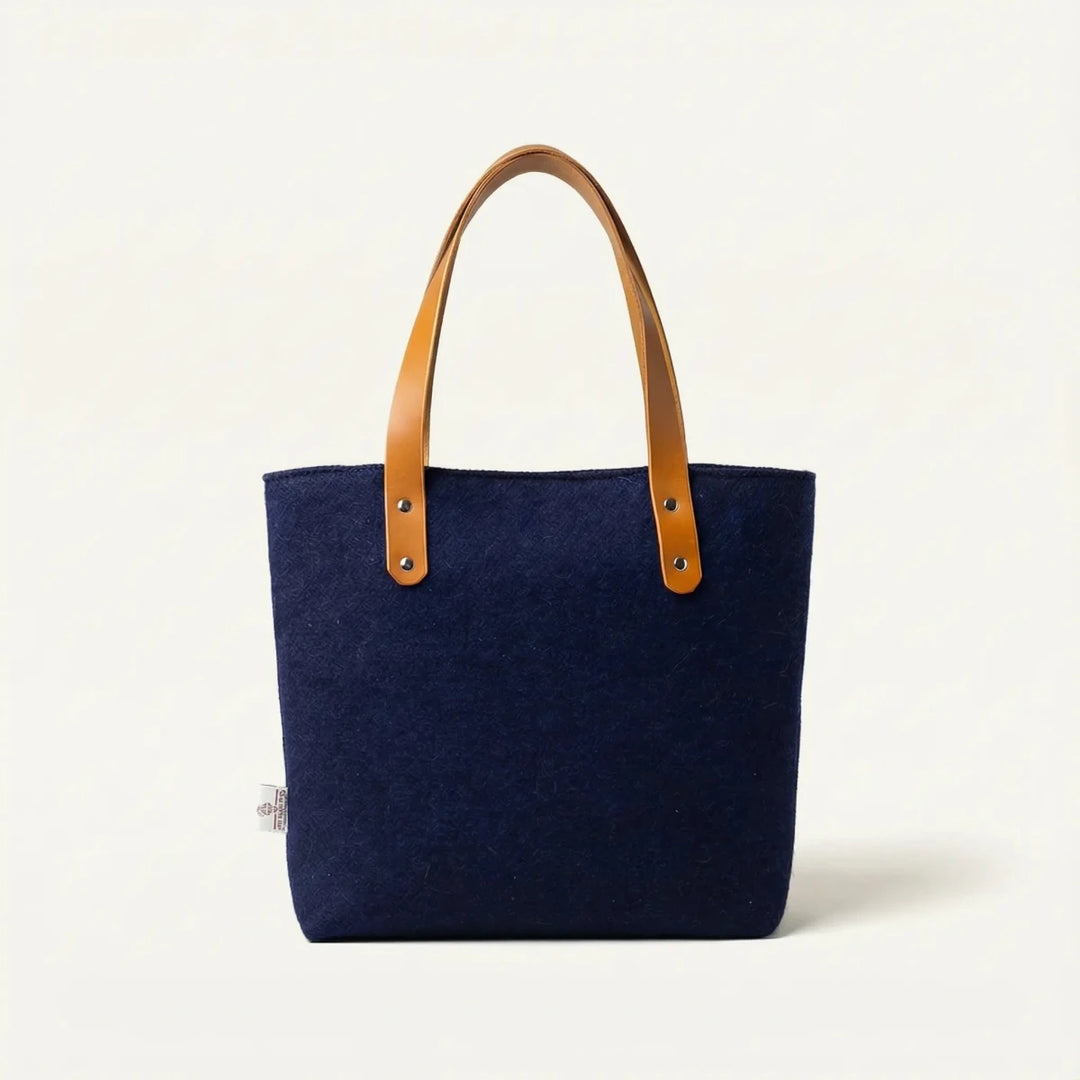 Navy Harris Tweed tote bag with tan leather handles, photographed front-on against an off-white studio background