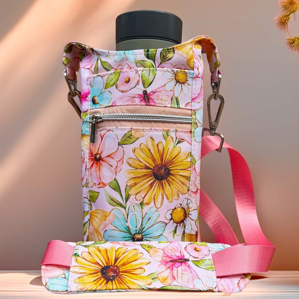 Floral bottle carrier bag in pastel tones, featuring pink and yellow blooms, photographed with warm natural sunlight on a neutral surface. Artisan-crafted in Wales by Emma Easter Handcrafted.