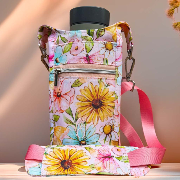 Floral bottle carrier bag in pastel tones, featuring pink and yellow blooms, photographed with warm natural sunlight on a neutral surface. Artisan-crafted in Wales by Emma Easter Handcrafted.