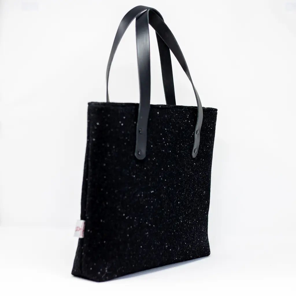 Angled side view of the black Harris Tweed tote bag with Harris Tweed® and black leather handles by Emma Easter Handcrafted.