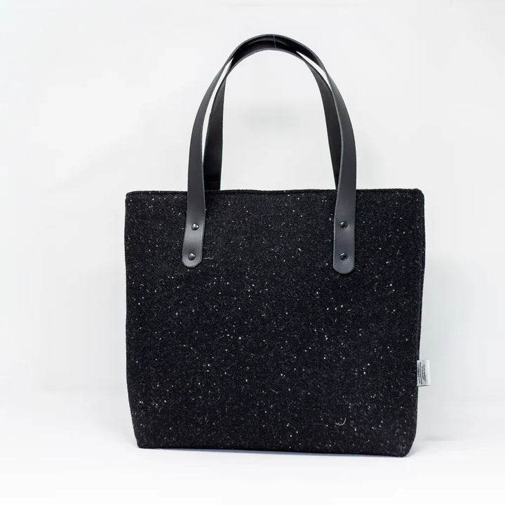 Front view of the black Harris Tweed tote bag with black leather handles, handcrafted in Wales by Emma Easter