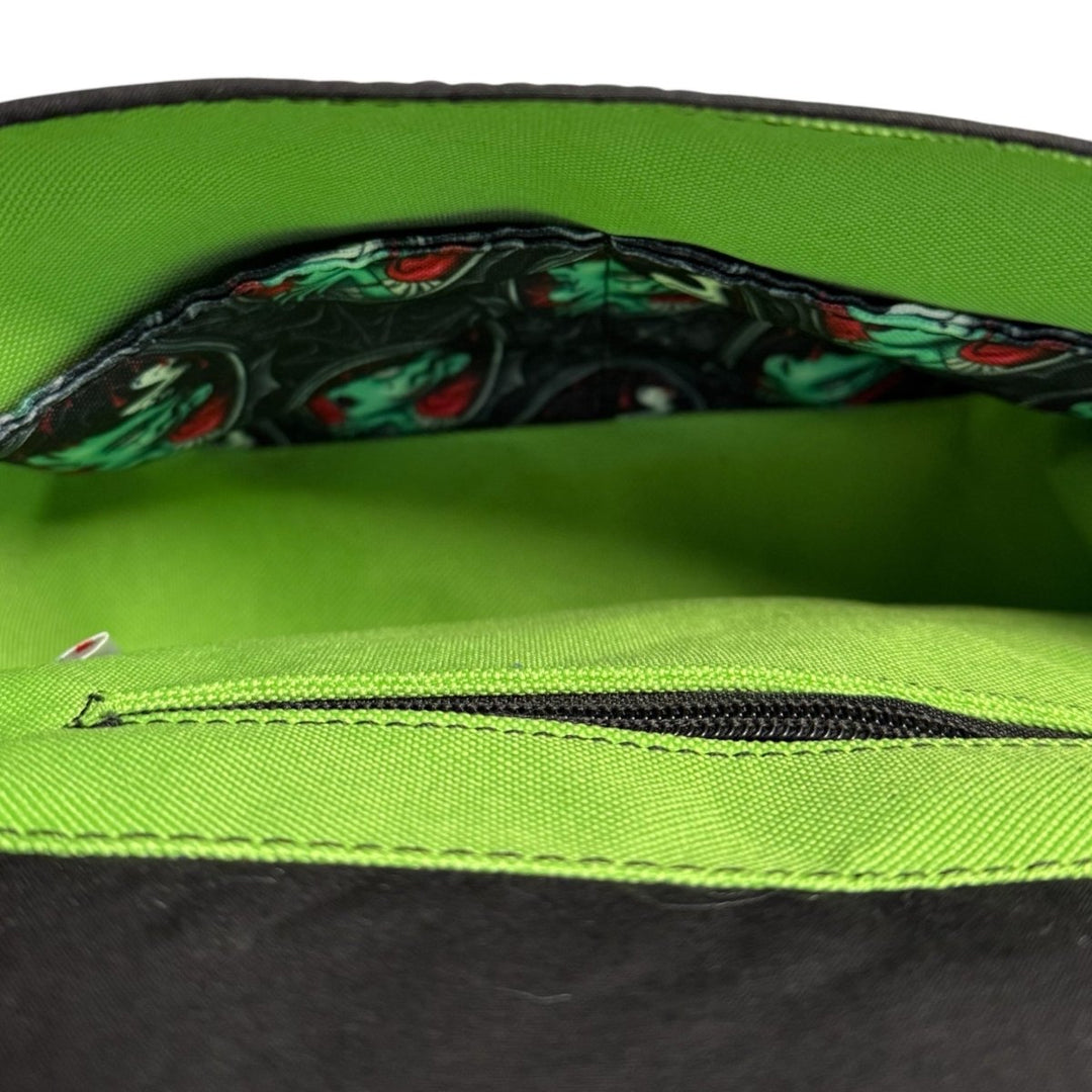View inside a handmade crossbody bag showing a bright green waterproof lining with a divided slip pocket in the matching Zombie Bride print.